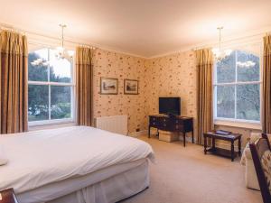a bedroom with a bed and a tv and windows at The Forest Country House B&B in Newtown