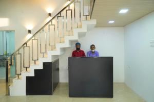 two men standing behind a podium in front of a staircase at Hotel Siddharth in Tanakpur
