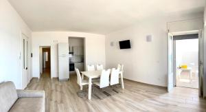 ein weißes Wohnzimmer mit einem Tisch und Stühlen in der Unterkunft Viva Vista Mare Trilo Primo Piano in Porto Cesareo