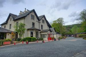 Une grande maison blanche avec des poteaux rouges dans la rue dans l'établissement Philipburn Hotel, BW Signature Collection, à Selkirk