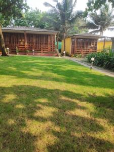 a green yard with a building in the background at Sea Front Beach Huts in Patnem