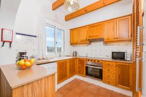 a kitchen with wooden cabinets and a counter top at Villa Jasmin in Sant Lluis