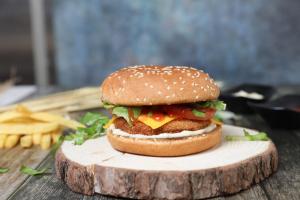 a hamburger on a bun sitting on a wooden table at منتجع قرية الفقرة in As Sudayrah