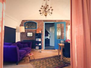 a living room with a purple couch and a brick wall at Vrijstaand Koetshuis Marron in Barsingerhorn