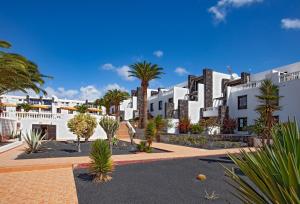 rząd białych budynków z drzewami i palmami w obiekcie Apartment Caleton Blanco, central Puerto del Carmen w Puerto del Carmen