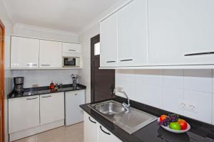 kuchnia z białymi szafkami, zlewem i miską owoców w obiekcie Apartment Caleton Blanco, central Puerto del Carmen w Puerto del Carmen