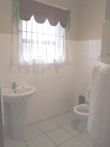 a bathroom with a toilet and a sink and a window at Reheifo Lodge in George