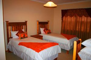 a hotel room with two beds with red sheets at Reheifo Lodge in George