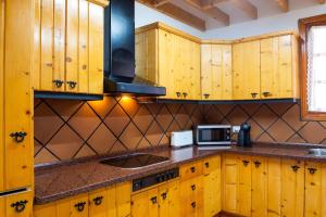cocina con armarios de madera y microondas en Villa NARE - Casa típica majorera, en Villaverde