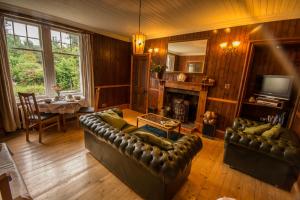 a living room with a leather couch and a fireplace at Westward Bed and Breakfast in Cannich