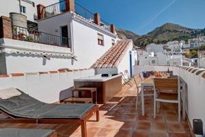 a balcony with tables and chairs on a building at Casa Beaumont - awesome Andalusian townhouse in Cómpeta