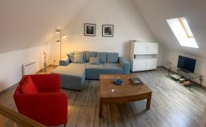 a living room with a blue couch and a red chair at Confortable duplex au cœur de la campagne Picarde à 1h de Paris in Biermont