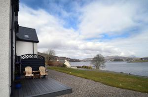 two chairs sitting on a deck near a body of water at Scorr House Apartment in Portree