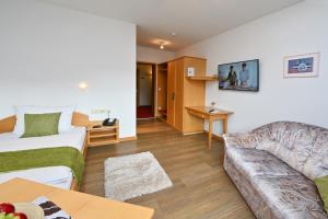 ein Hotelzimmer mit einem Bett und einem Sofa in der Unterkunft Gasthaus - Hotel Alt Fürstätt in Rosenheim