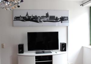 TV de pantalla plana en la parte superior de una pared blanca en Sundappartement, en Stralsund