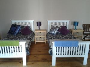 twee witte bedden met kussens op de kamer bij Little Lotta Cottage in Caledon