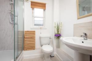 a white bathroom with a toilet and a sink at 2 Bedroom Apartment in a Quiet Neighbourhood in St. Andrews +14 photos
