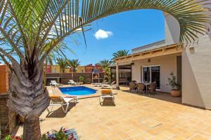 a patio with a palm tree and a swimming pool at Villa privada en Corralejo in Corralejo