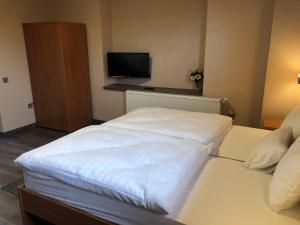 uma grande cama branca num quarto com televisão em Katalin Motel & Étterem em Berettyóújfalu