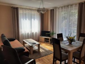 Apartamenty ,,Trzy Sosny'' Rymanów-Zdrój في ريمانوف-زدروي: غرفة معيشة مع طاولة وأريكة وغرفة طعام
