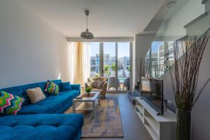 sala de estar con sofá azul y TV en VESTA - El Gouna Residence en Hurghada
