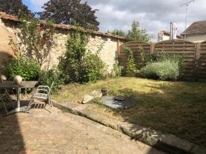 a yard with a table and a chair and a fence at Studio de la porte de Samois in Moret-sur-Loing