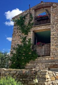 a stone building with a balcony with flowers on it at La Grange de la Lavande in Lardiers