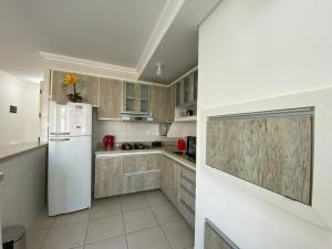 a kitchen with a white refrigerator and cabinets at Lindo apartamento mobiliado in Capão da Canoa