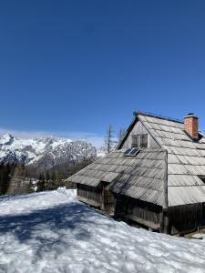 un granero en la nieve con montañas en el fondo en Velika Planina - Chalet Rušovc - Location with fully privacy, en Stahovica