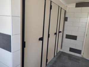 a bathroom with two doors and a tile wall at Camping Parc de la Brenne in Lignac