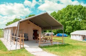 a tent with a picnic table in a field at Camping Parc de la Brenne in Lignac