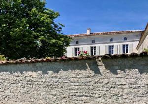 una casa blanca detrás de una pared de piedra en Le Pigeonnier Gite, en Verrières