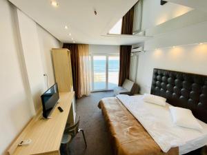 a hotel room with a bed and a desk with a television at Ella by the sea Residence in Mamaia Sat/Năvodari