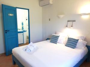 a bedroom with a large white bed with a blue door at Résidence Belvedere de Palombaggia in Porto-Vecchio