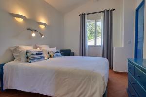 a bedroom with a white bed with pillows and a window at Résidence Belvedere de Palombaggia in Porto-Vecchio