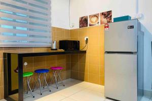 a kitchen with a counter with stools and a refrigerator at Tiara East Broga Homestay in Semenyih