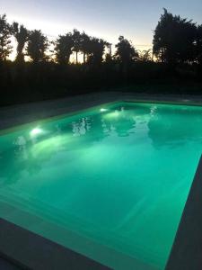 a large swimming pool with blue water at dusk at Le Pigeonnier Gite in Verrières