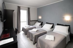 una camera d'albergo con tre letti e una televisione di J Hotel a Orbassano