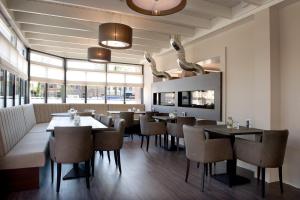 a restaurant with tables and chairs and windows at Hotel-Restaurant Thuis! in Dinteloord