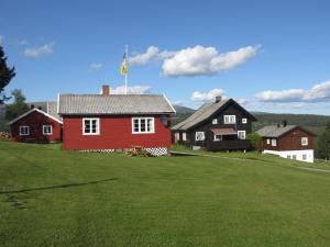 a red house with a flag on top of a field at Skåbu Hytter og Camping in Skåbu