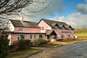 uma casa cor-de-rosa à beira de uma estrada em Savoy Country Inn em St Clears