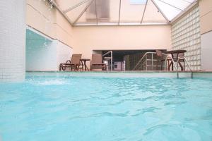 a swimming pool with blue water in a building at Belo Horizonte Plaza in Belo Horizonte