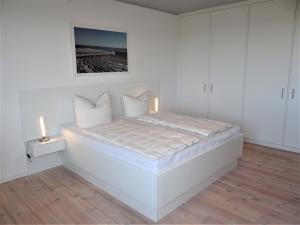 a white bed in a white room with a candle at Speicher Residenz Barth E3 App 7 in Barth