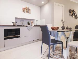 una cucina con armadi bianchi, tavolo e sedie di Vernazza Luxury Apartment a Vernazza