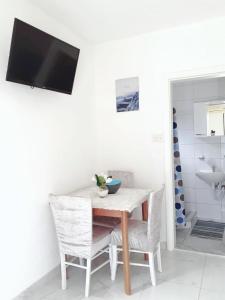 a dining room table with chairs and a television on a wall at Apartmani Leženić Dada in Neum