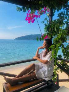 a woman sitting on a bench by the water at Tioman Cabana Bed & Breakfast in Tioman Island