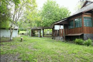 a large wooden building with a grass yard in front of it at Садиба "БІля Виру" in Buki