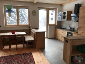 uma cozinha com uma mesa de madeira e uma cozinha com janelas em Cësa Gredine em Ortisei