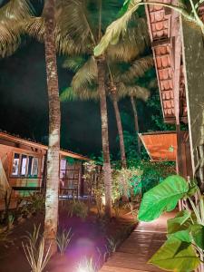 a house with palm trees and a wooden deck at Pousada Alquimista in Fernando de Noronha