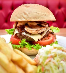 uma sanduíche num prato com batatas fritas e uma salada em Sinclair Guest House em Abuja